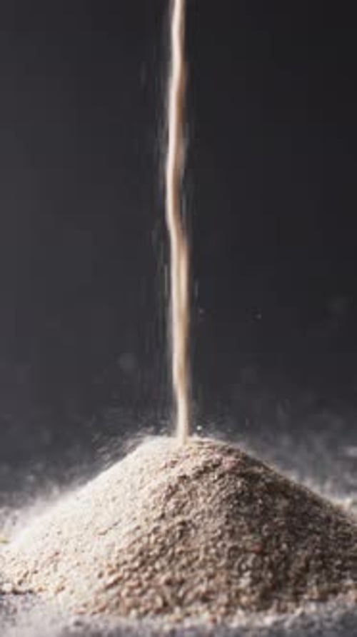Vertical video of close up of heap of sand grains and copy space on black background