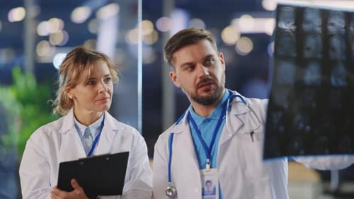 Couple of Caucasian Medical Workers Talking in Office Cabinet Discussing MRI XRay Photograph for