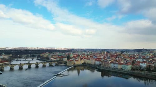 Drohnenaufnahme des Prager Stadtbildes mit der Karlsbrücke, die sich unter blauem Himmel auf der Moldau spiegelt