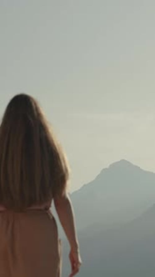 Woman Looks at Mountain Range From High Vantage