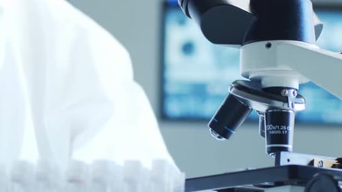 Scientist Analyzing Blood Samples with Microscope in Lab