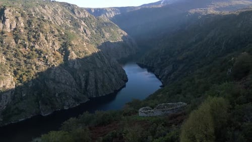 La luz cálida se refleja en los escarpados acantilados y traza el sereno flujo del río