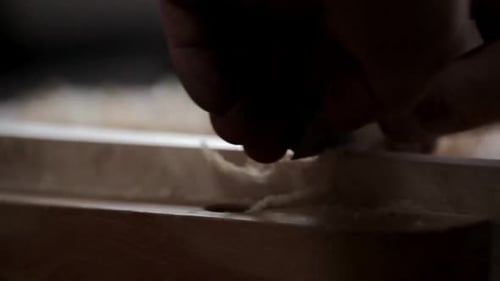 Carpenter in calgary Canada carefully planes a wood block in slow motion