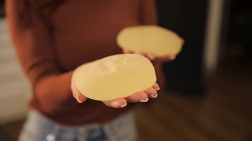 Woman Holds Two Gel-Like Breast Implants