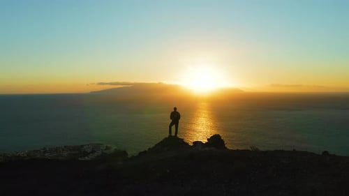 Hiking Man in Mountains Watching Sunset and Horizon Over Beautiful Ocean Water Landscape