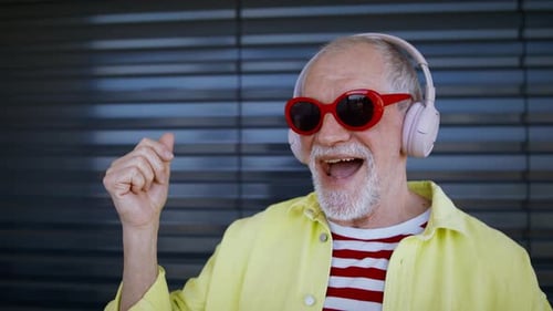 Homme âgé avec lunettes de soleil et écouteurs écoutant de la musique et s'amusant