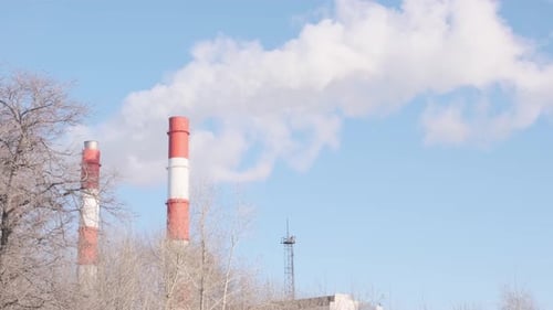 Schornsteine des Kraftwerks am blauen Himmel Weißer Dampf aus der roten Röhre in der Nähe Weißer Rauch aus dem Schornstein