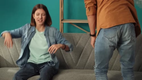 Close Up of Living Room Couple Taking Off the Film From Sofa in New Apartment Sitting Tired Talking