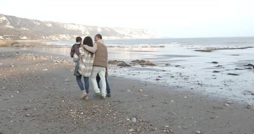 Family walking on the beach on vacation in autumn