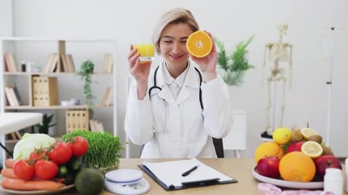 Smiling Dietician with Orange and Juice at Desk