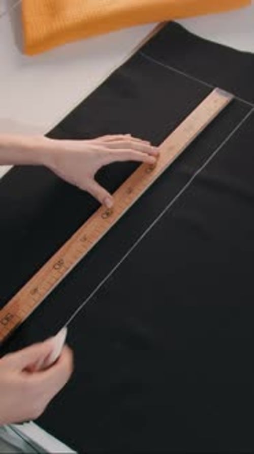 Woman Tracing Sewing Pattern with Ruler in Studio