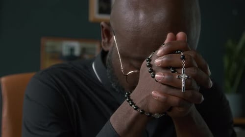 Man Praying with Rosary Beads Indoors