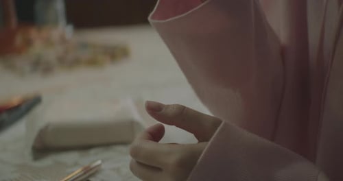 Nahaufnahme einer jungen Frau, die sich ins Zimmer setzt und ein Taschentuch herausnimmt, um sich den Kopf abzuwischen