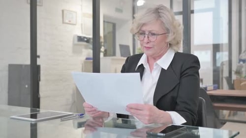 Woman Reviews Documents at Bright Glass Desk
