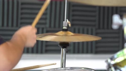 Close up of a musician or drummer in a music studio sitting in front of a drum set playing the cymba