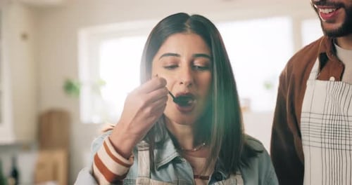 Woman Sampling Homemade Food in Kitchen with Friend
