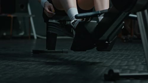 Woman on Rowing Machine Tying Laces and Working Out