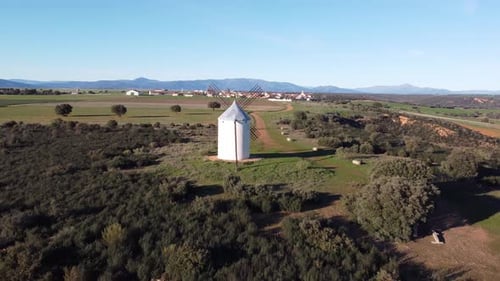 aerial approaching to traditional white windmill green grass and gold daylight