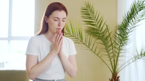 Woman in Prayer with Hands Clasped Indoors