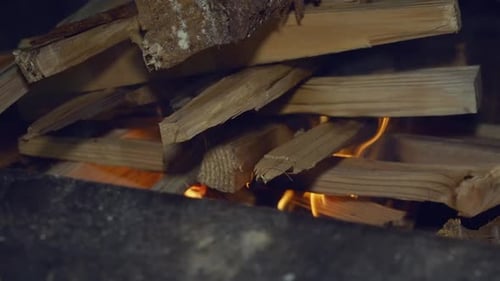 Dry chopped firewood stacked in camp fire sags as it burns from below
