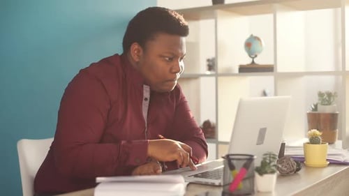 Thinking Young African American Man Writing and Working on Laptop in Office Sunlight Business Person