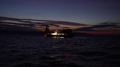 Fisherman On A Lighted Boat Fishing At The Adriatic Sea During Daybreak. - Static Shot