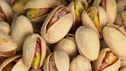 Roasted pistachios rotate on a black background. Salted pistachio nuts for beer background close