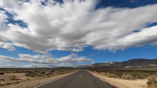 Beautiful Nature Scenery While Driving On The Desert Road In Mojave, California Under The Fluffy Whi