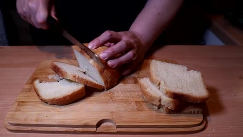 Person cutting bread on cutting board in kitchen