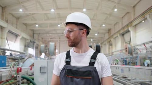 Confident Engineer in Uniform Goes Through an Industrial Factory