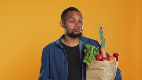 Hombre seguro haciendo malabares con una manzana verde ecológica frente a la cámara