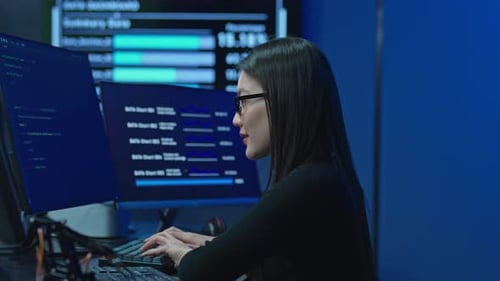 Programmiererin arbeitet an mehreren Monitoren im Büro