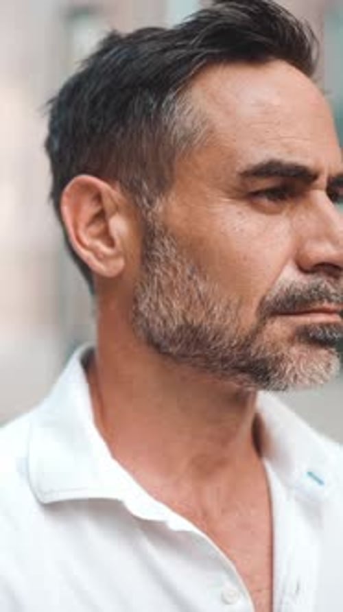 Close-up Businessman mature looks turns his head at the camera and smiles