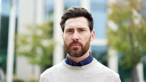 Portrait of confident serious male professional standing on street near business office building