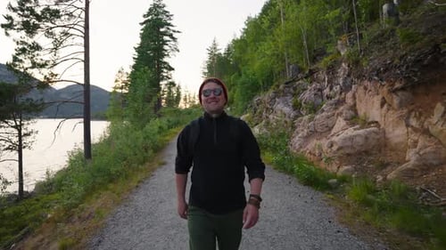Smiling Man Walks Path Near Lake at Sunset