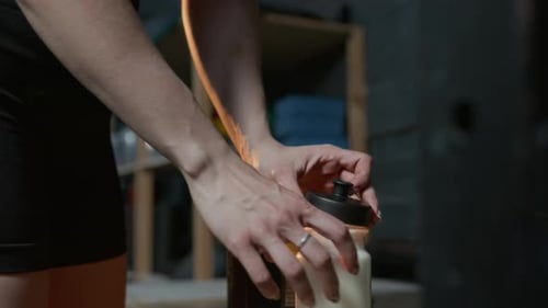Athletic Girl Adding Spoon of Protein to Milk and Shaking Gym Bottle