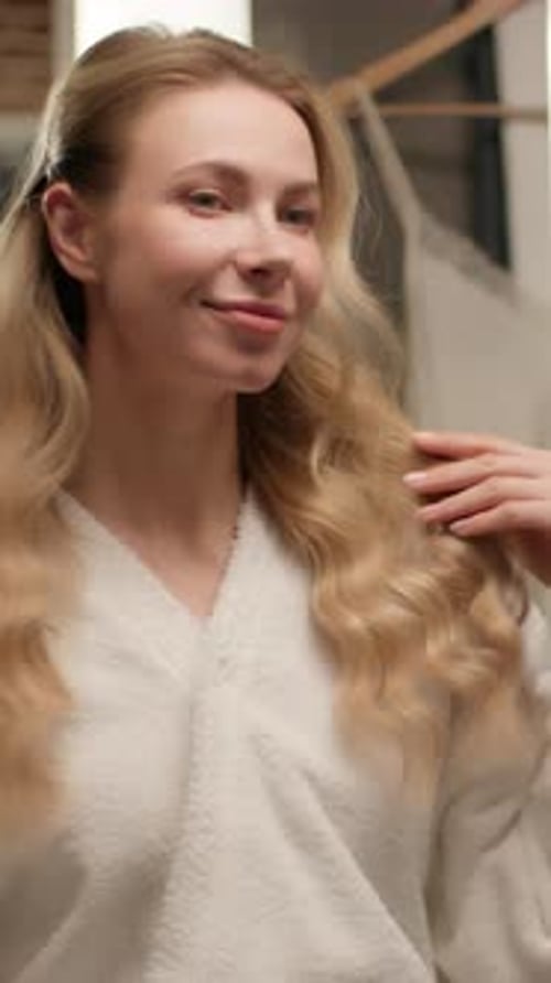 Woman Fixing Blonde Hair in the Mirror
