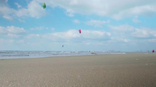 Kite surfers riding over ocean near sandy beach