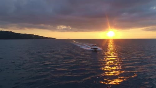 Luftparallaxe, aufgenommen um ein Schnellboot auf dem Wasser mit Sonnenuntergang im Hintergrund