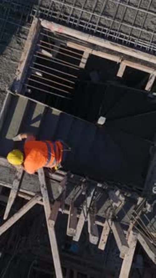 Vídeo vertical de ingenieros supervisando una grúa levantando vigas mientras los trabajadores construyen paredes y las colocan