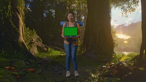 Full Body Of Asian Female Hiker Showing Mock Up Green Screen Laptop While Exploring Forest Nature
