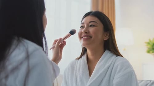 Makeup Application Process Inside a Bright Room With Two Women Preparing for an Event in Quality