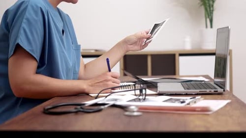 Medical Professional Reviewing Scan at Desk