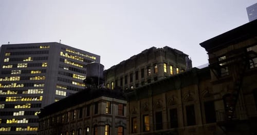 A medida que el crepúsculo desciende, los edificios de la ciudad cobran vida con ventanas brillantes