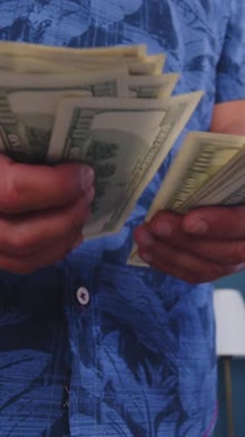 Man Counts Stack of One Hundred Dollar Bills