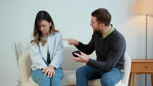 Angry Man Yelling at Sad Woman on Couch
