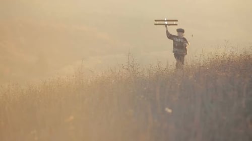 Happy Young Man Running with Wooden Airplane on Autumn Hill