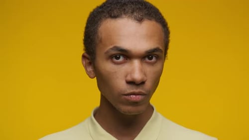 Young Adult Man's Intense Portrait Against Yellow Background