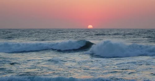 Slow motion Dramatic pink sunrise reflected over breaking waves at the beach, Durban, Kwazulu-Natal.