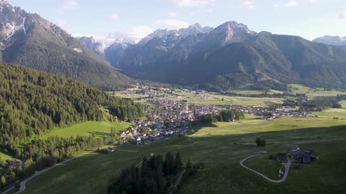 Drone flying towards the city with the Church of San Giovanni Battista in the center of the Dolomite